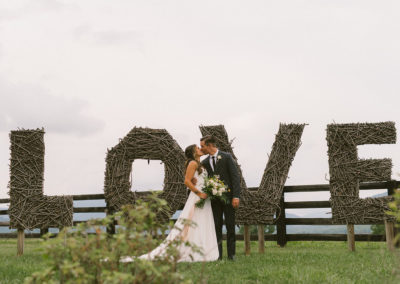 couple kissing in front of "LOVE" sign