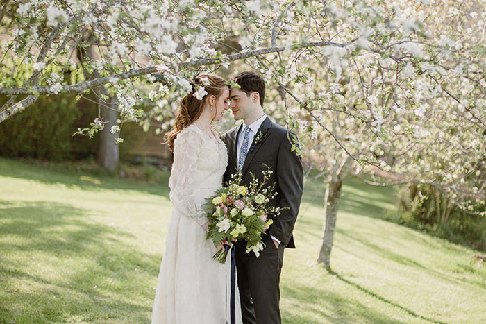 bride and groom standing under blooming tress