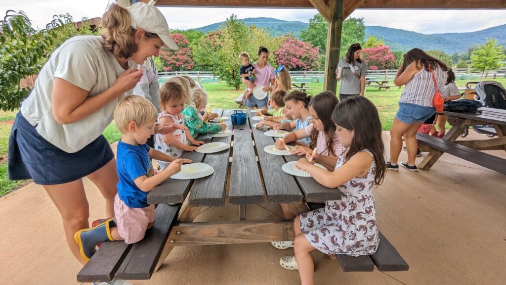 woman and kids making a craft together outside